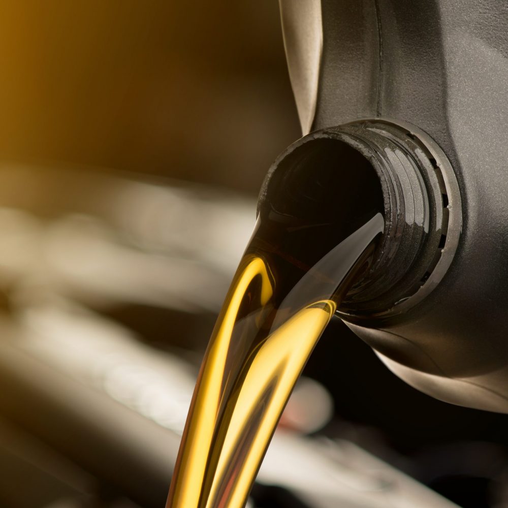 Pouring oil lubricant motor car from black bottle on isolated white background